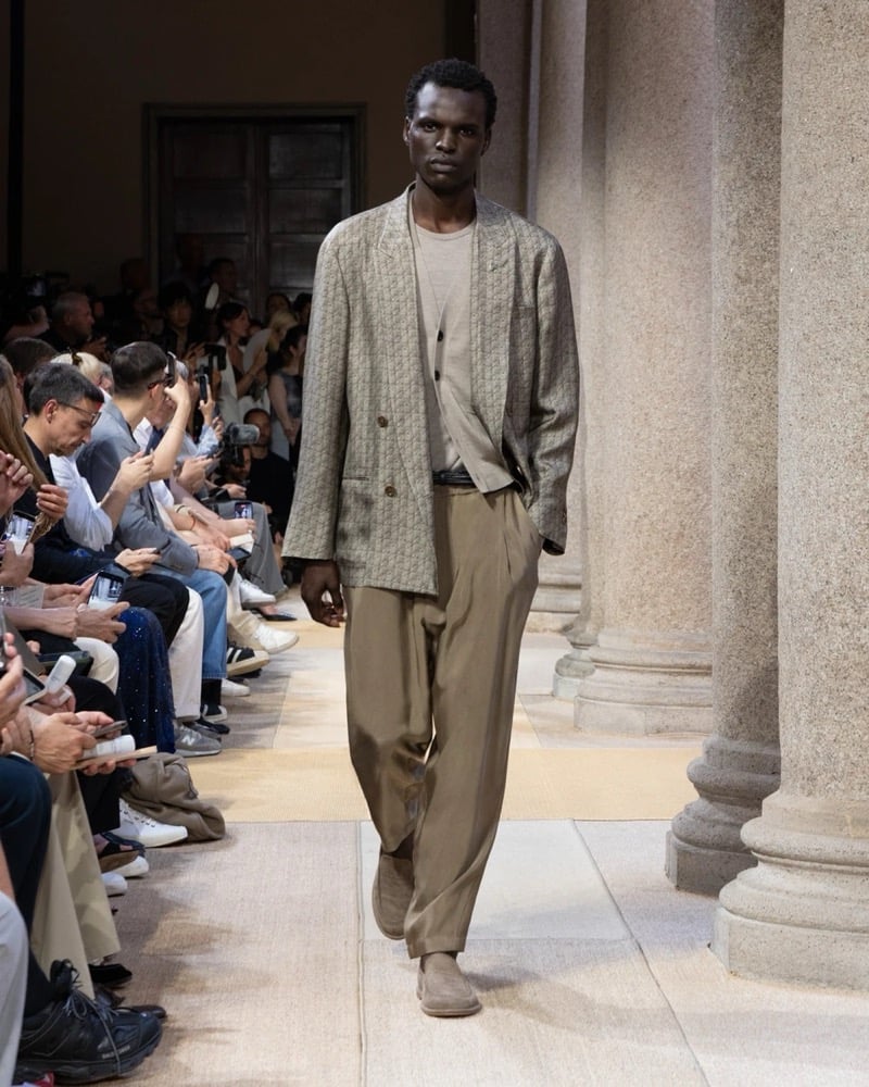 Model wears an oversized double-breasted geometric-patterned linen blazer with notch lapels, layered over a tee and worn with wide pleated trousers