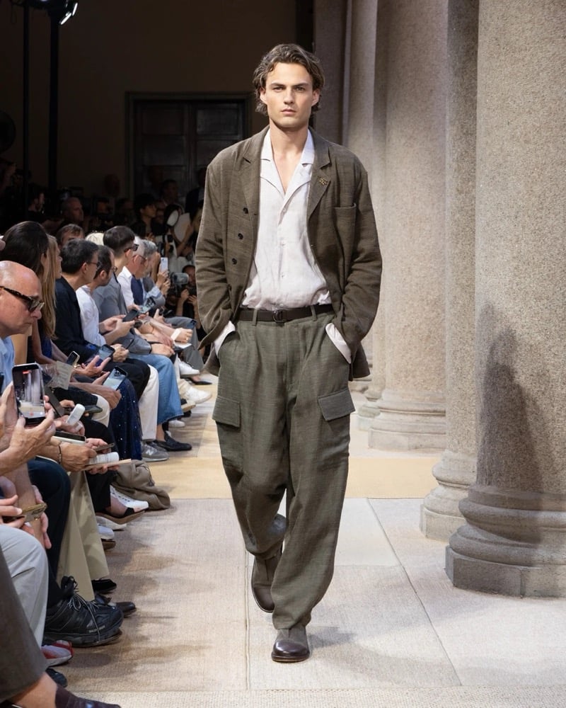Model wears a relaxed double-breasted textured-linen jacket over an open shirt, paired with wide pleated linen cargo trousers