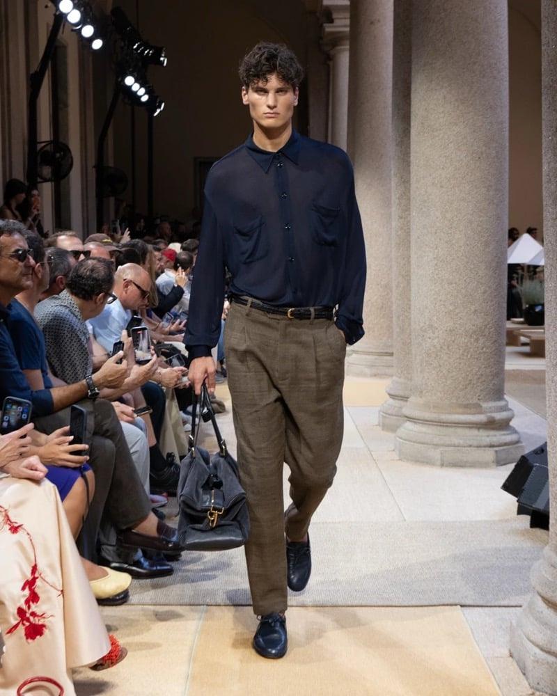 Model wears an oversized sheer long-sleeve button-up shirt with a chest patch pocket, paired with wide pleated linen trousers