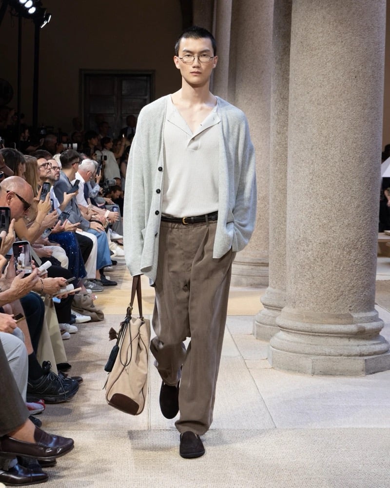 Model wears a marled long-sleeve cardigan layered over a soft V-neck top, paired with wide pleated linen trousers