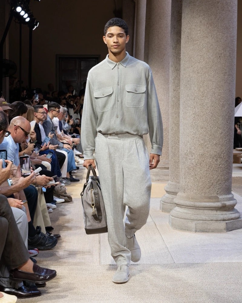 Model wears a long-sleeve overshirt with twin chest flap pockets tucked into matching wide pleated drawstring linen trousers