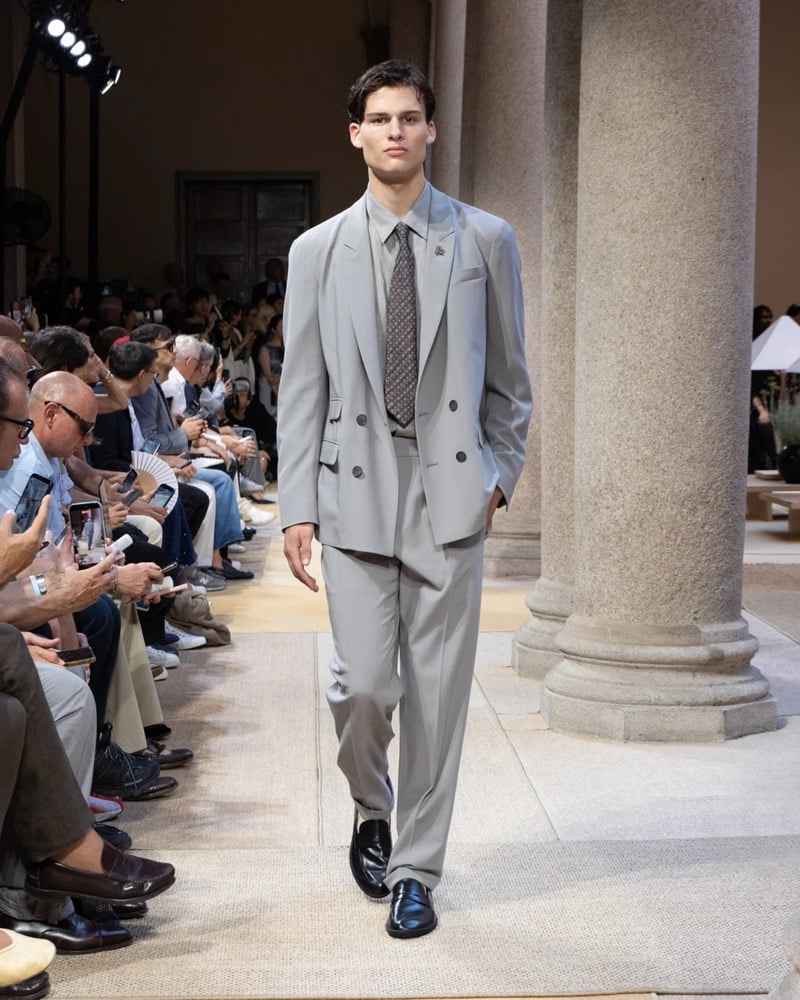 Model wears a double-breasted peak-lapel suit layered over a shirt and patterned tie