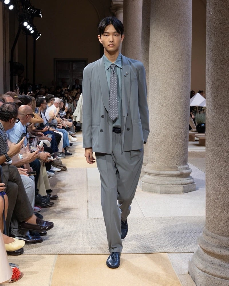 Model wears a double-breasted peak-lapel suit layered over an open camp-collar shirt and patterned tie