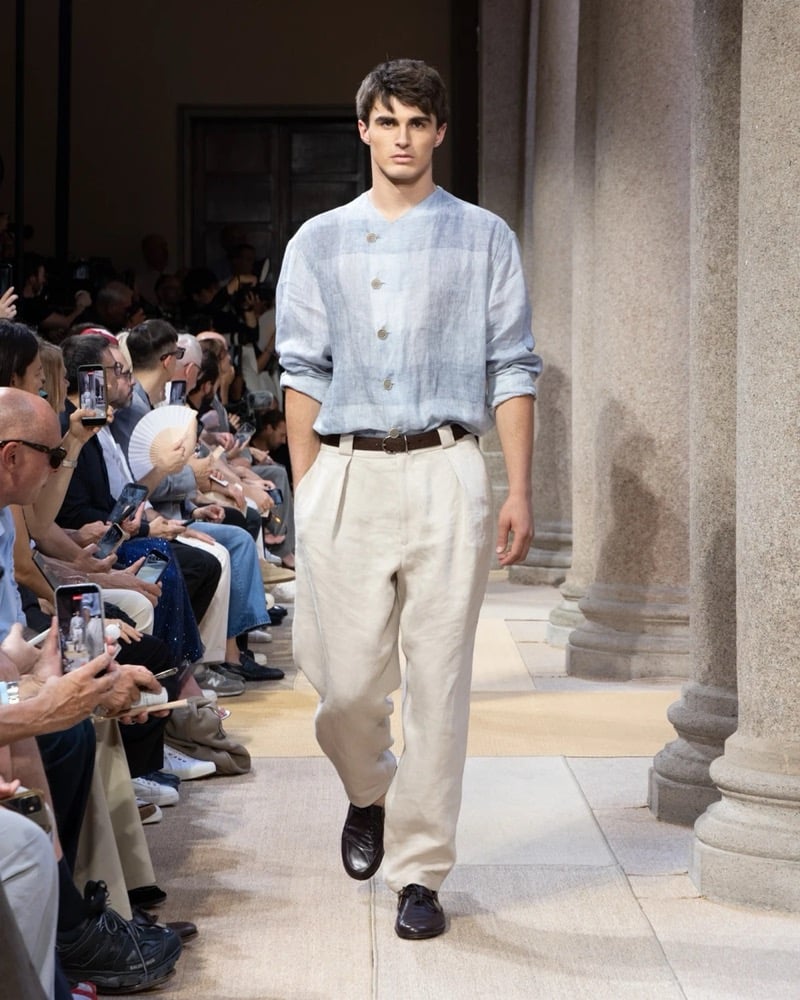 Model wears a band-collar paneled linen overshirt with a four-button placket, paired with wide pleated linen trousers