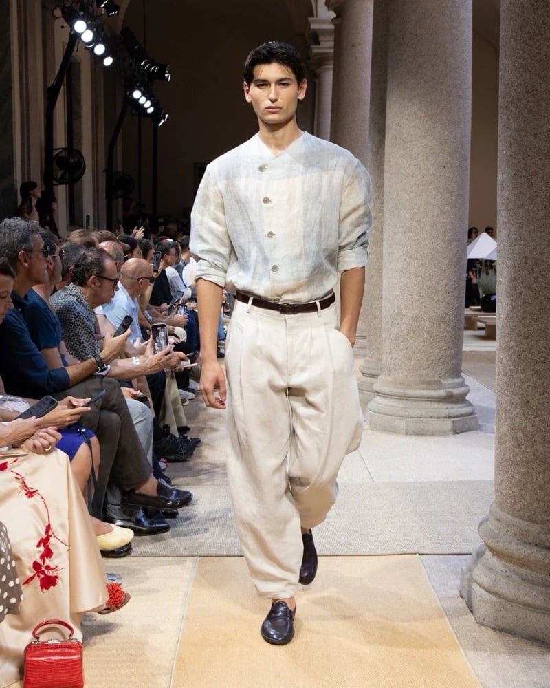 Model wears an asymmetric-button band-collar linen overshirt paired with wide pleated drawstring linen trousers