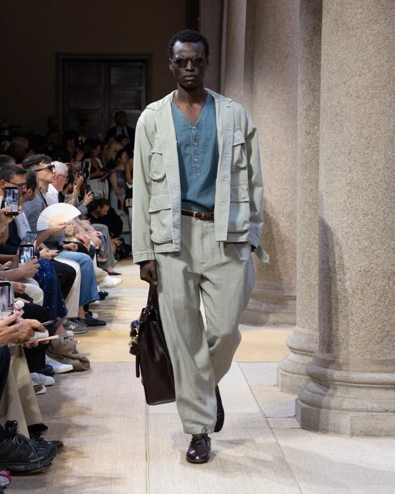 Model wears a soft cotton safari jacket with four flap pockets layered over a tunic henley, paired with wide pleated linen trousers