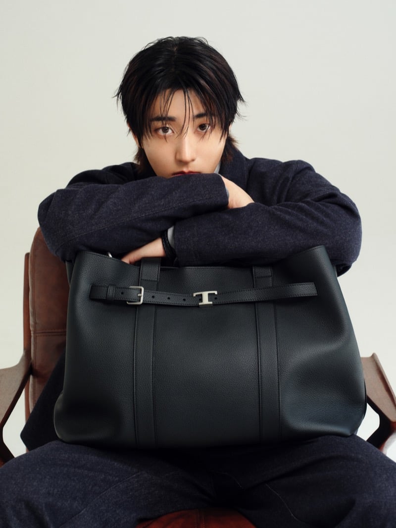 Han Jisung rests his arms over a black leather Tod's T tote, wearing a wool jacket against a soft studio backdrop