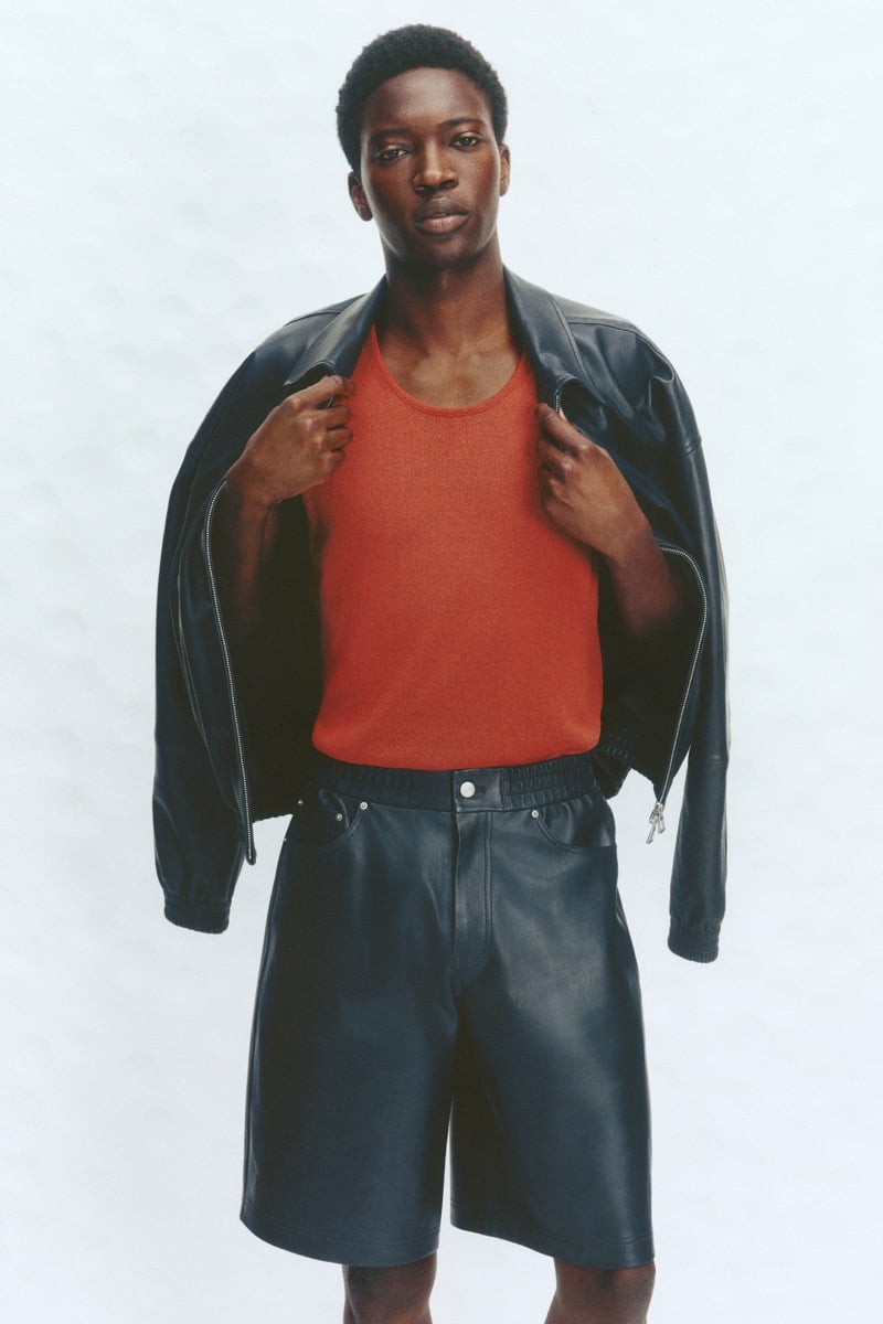 Limamu Mbaye wears a dark leather zip blouson open over a red ribbed tank with matching dark leather shorts