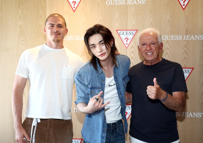 Hyunjin standing between Nicolai Marciano and Paul Marciano at the GUESS Jeans Melrose pop-up