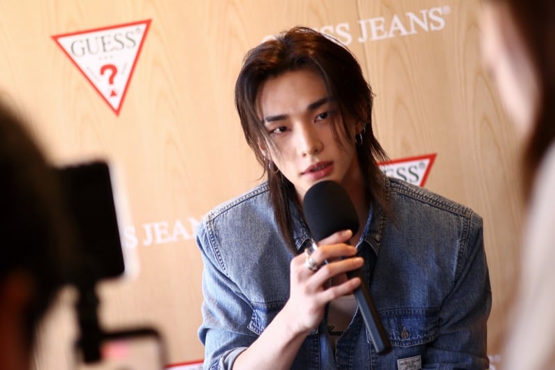 Hyunjin speaking into a microphone during a press interview at the GUESS Jeans Melrose pop-up