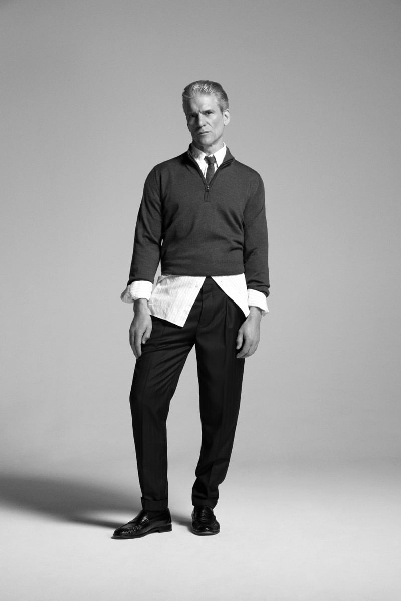 Felix Friedman models the John Smedley Tapton extra fine merino half-zip funnel-neck pullover layered over a striped shirt with tailored trousers