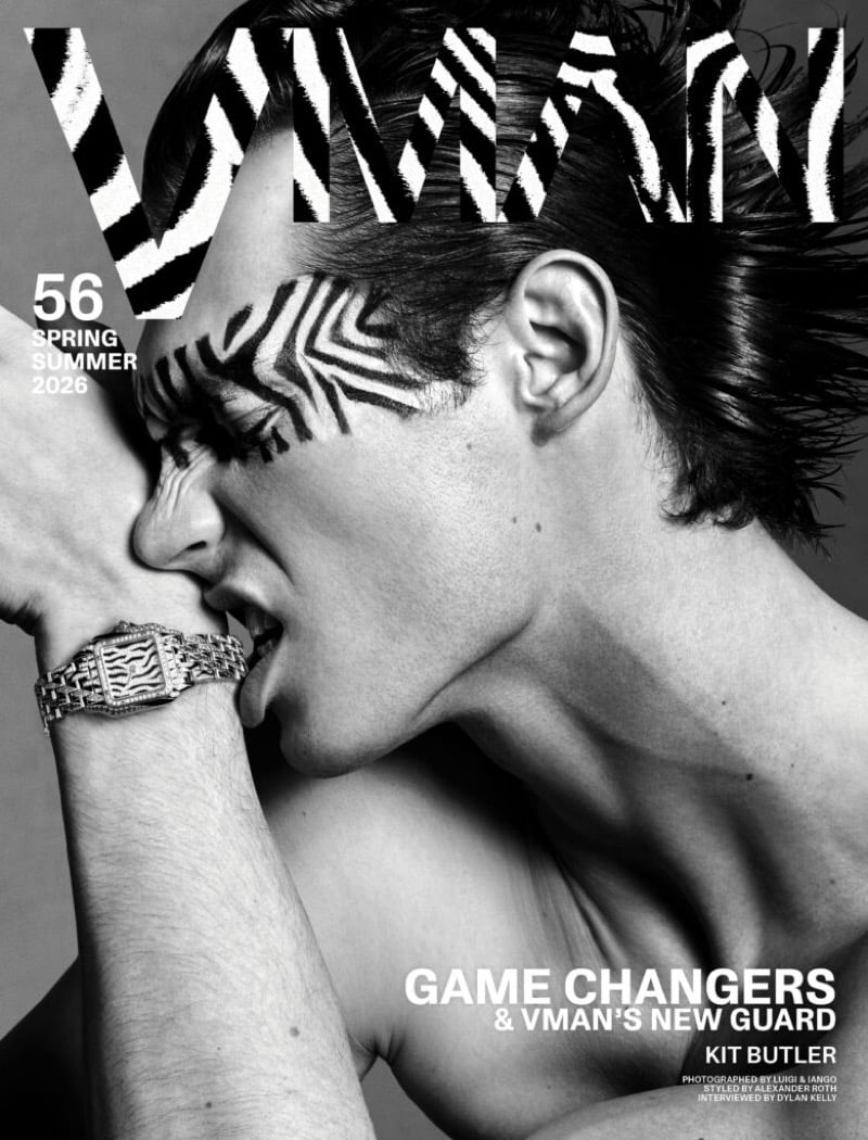 Kit Butler on the alternate VMAN spring-summer 2026 cover, bare-shouldered with zebra stripes painted across one cheek and the bridge of his nose, biting his own wrist where a silver bracelet watch sits, hair tousled
