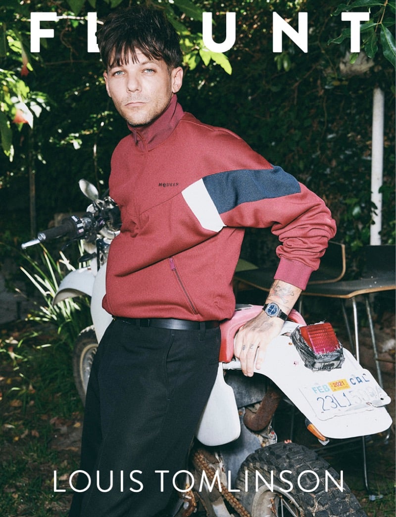 Louis Tomlinson covers Flaunt magazine perched against a dirt bike in a red color-block McQueen half-zip top with dark pants