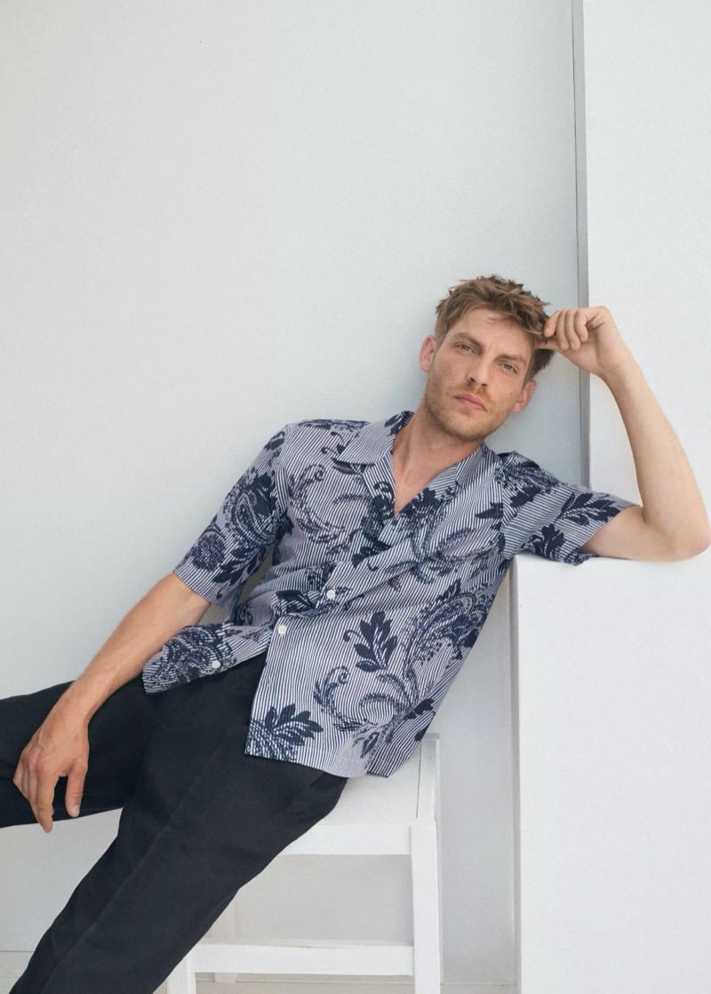 Baptiste Radufe wears a striped camp-collar shirt printed with navy paisley motifs and black tailored trousers for Mango Man summer 2026