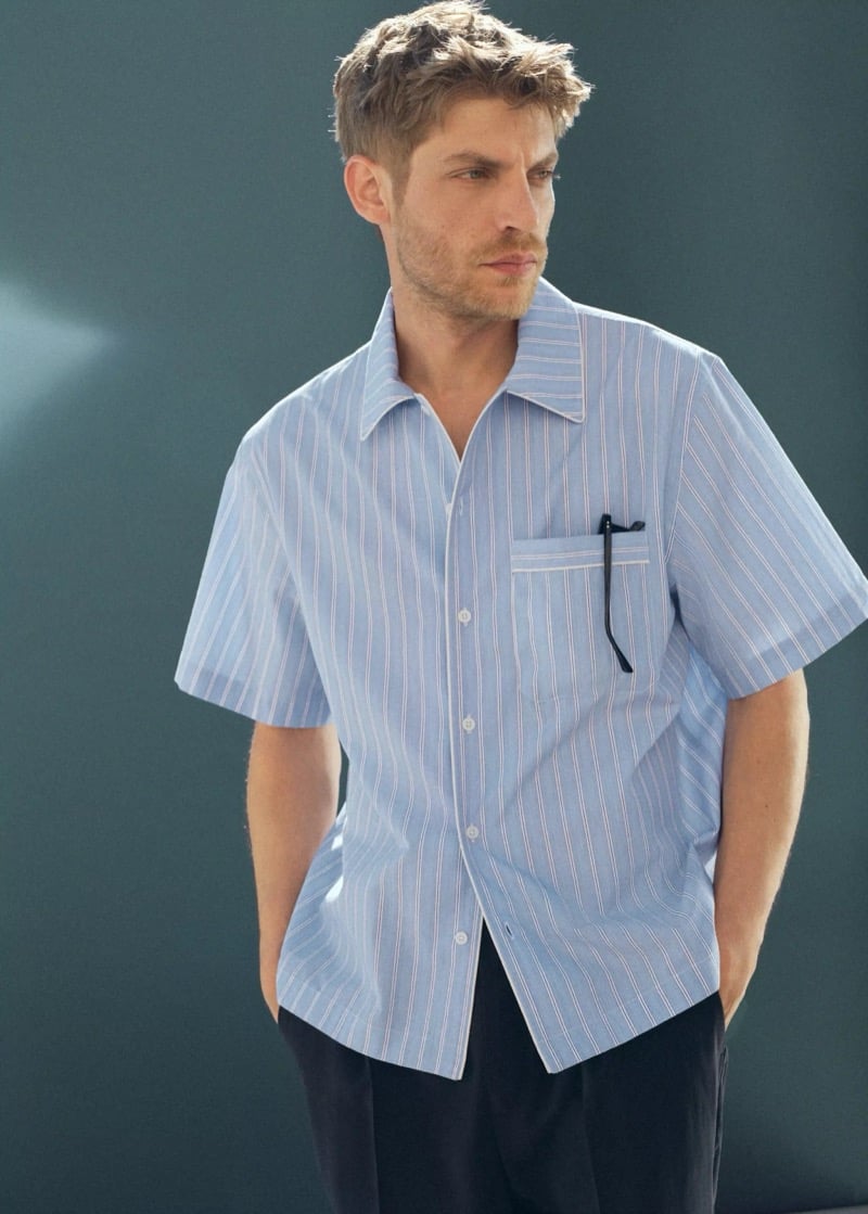 Baptiste Radufe wears a light blue striped short-sleeve camp shirt with navy pleated trousers for Mango Man summer 2026