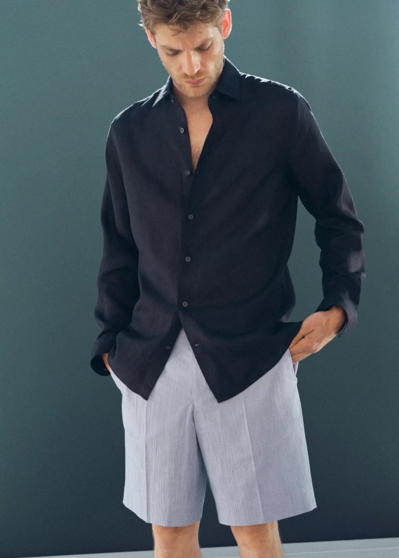 Baptiste Radufe wears a black linen button-down shirt with light gray pleated Bermuda shorts for Mango Man summer 2026
