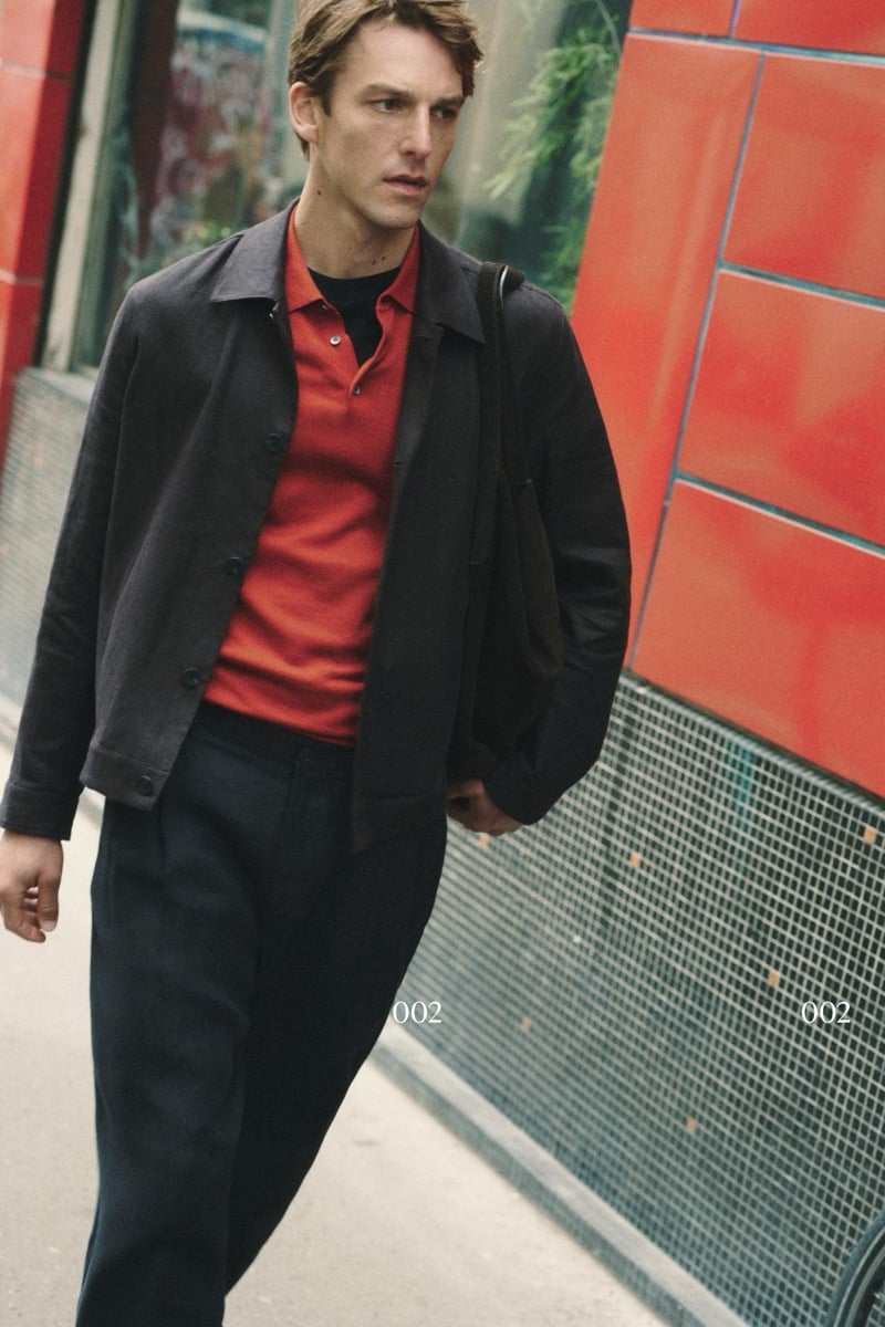 Quentin Demeester walking past a tiled facade in a Massimo Dutti soft blouson over a ribbed polo and tee with pleated trousers