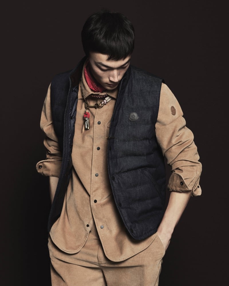 Model Pascal Thulin in a quilted down vest over a tan corduroy shirt and matching corduroy trousers, accessorized with a red bandana and a leather cord necklace with a key fob and small charms