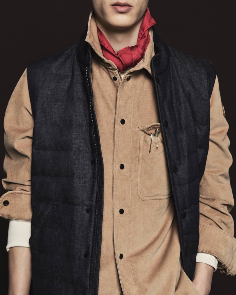 Close-up of a quilted down vest over a tan corduroy shirt with pencils in the chest pocket and a red bandana at the neck