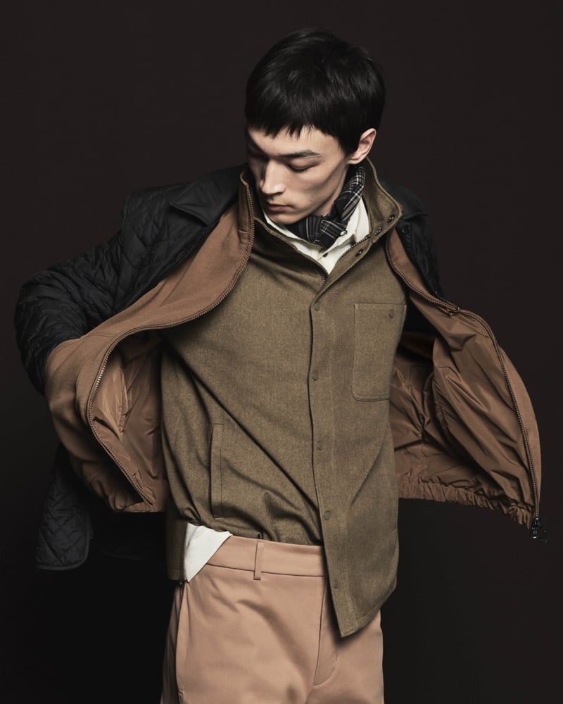 Model Pascal Thulin in a black quilted nylon jacket open over an olive wool shirt jacket, white shirt, and wool trousers