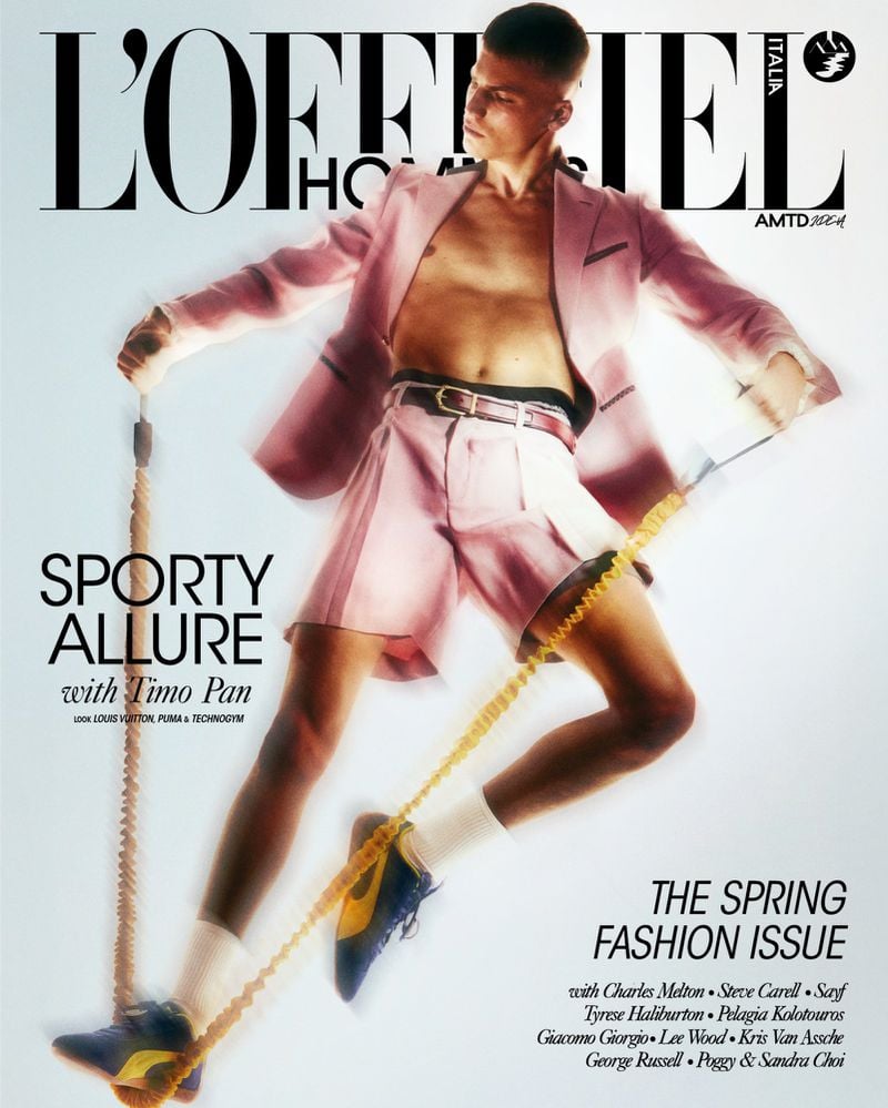 Timo Pan on the cover of L'Officiel Hommes Italia spring fashion issue in a pink Louis Vuitton single-breasted blazer over a bare chest with matching pleated pink shorts, a brown leather belt, white tube socks, and blue suede Puma sneakers, stretching a yellow Technogym resistance bungee between his hands and feet against a white backdrop, with the L'Officiel Hommes Italia masthead and 'Sporty Allure with Timo Pan' cover line