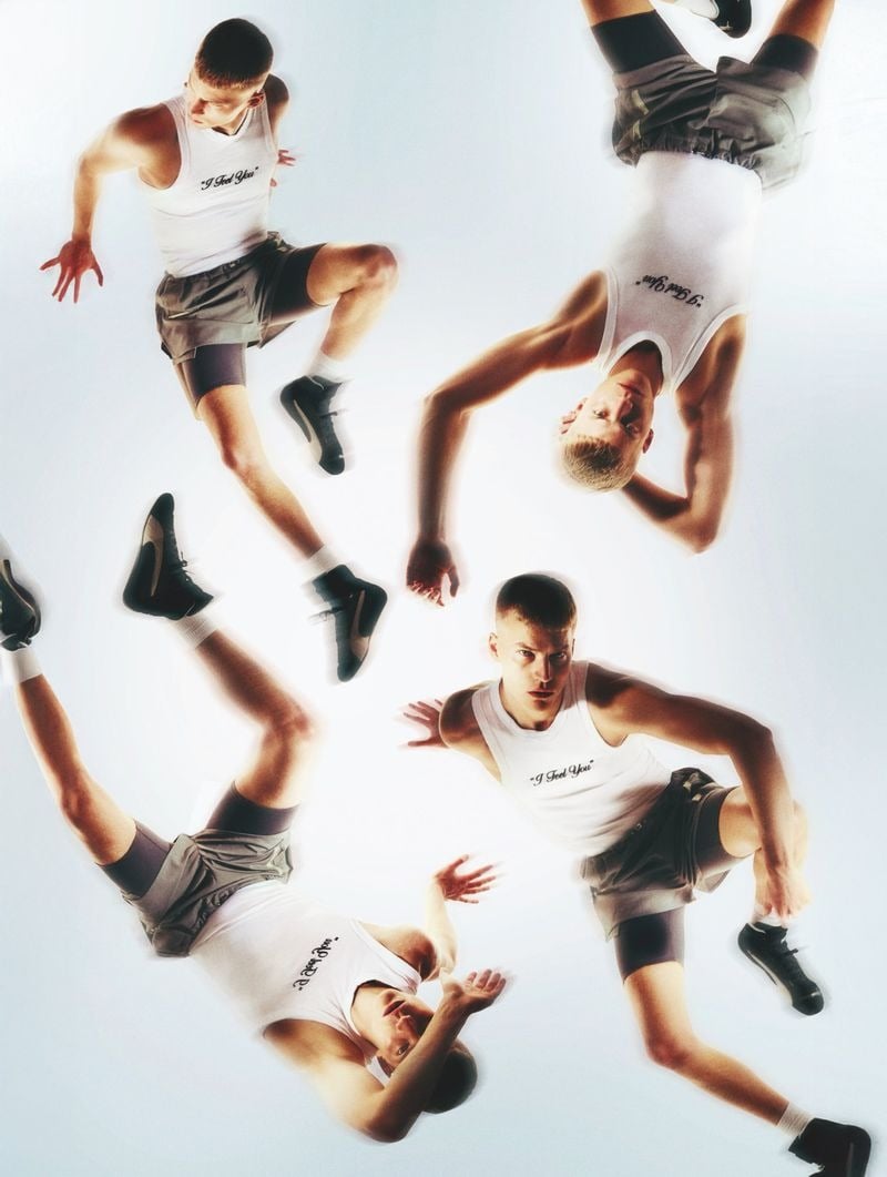 Quadruple-exposure composite of Timo Pan in white ribbed tank tops printed with the cursive script 'I Feel You,' paired with gray boxer shorts and black low-top sneakers with white socks, tumbling and leaping in four positions across a white backdrop