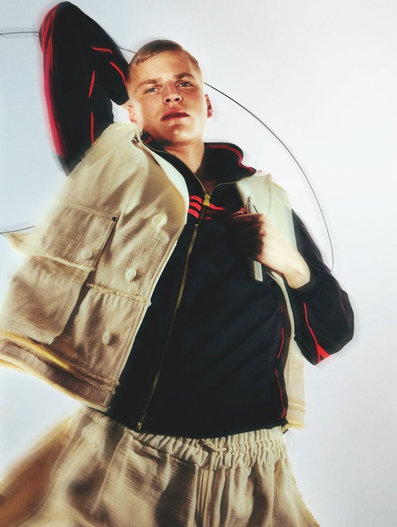 Timo Pan in a raw-edged vest layered over a navy track jacket with red and orange side stripes, paired with drawstring shorts