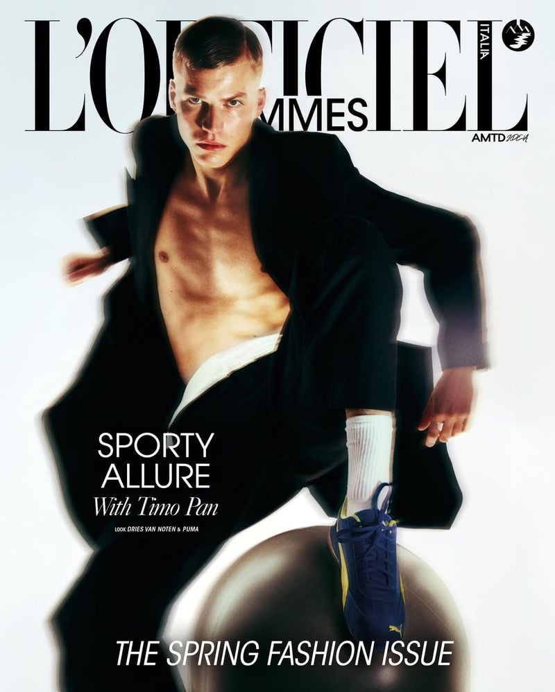 Timo Pan on a second L'Officiel Hommes Italia cover styled in an oversized black Dries Van Noten blazer over an open white waistband, white crew socks, and a navy and yellow Puma suede sneaker balanced on a gray exercise ball, the L'Officiel Hommes Italia masthead and 'Sporty Allure With Timo Pan' cover line printed across the white frame