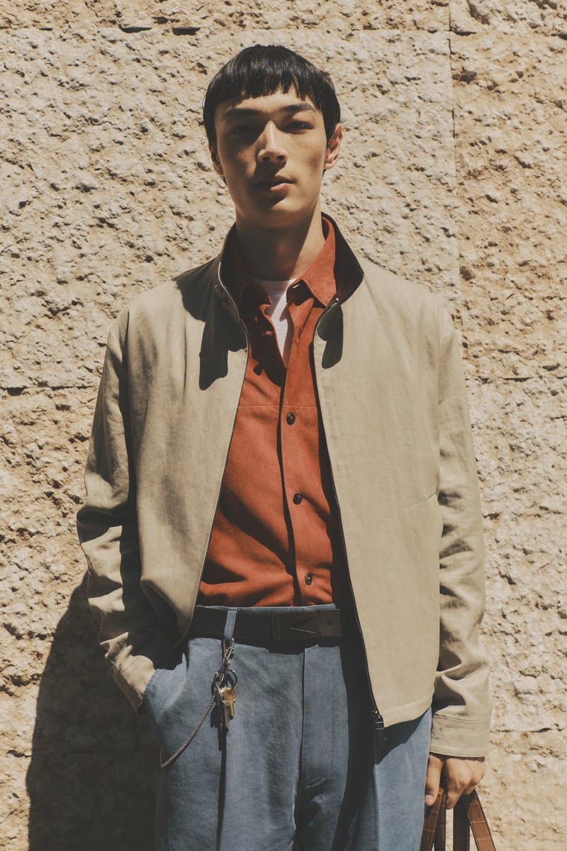 Model Pascal Thulin in a sand harrington jacket over a rust orange shirt and white tee, paired with pleated trousers and a leather belt with key chain