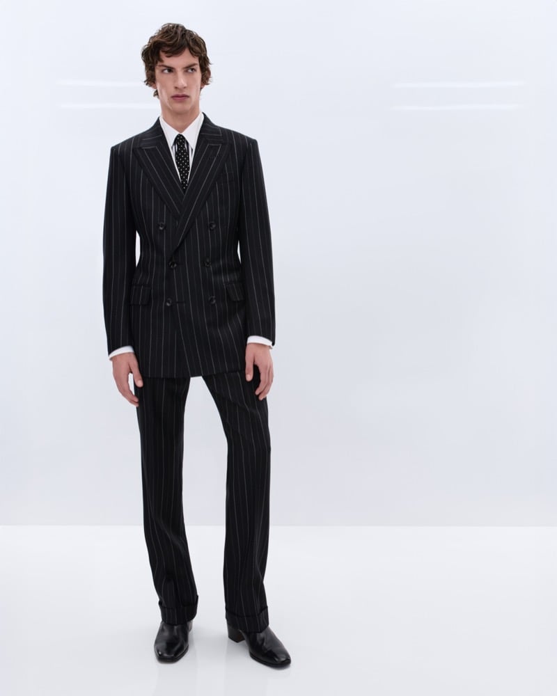 Elliot Belot wears a black double-breasted chalk stripe suit over a white shirt with a black polka dot tie