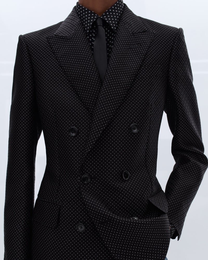 Samuel Elie wears a black double-breasted micro-dot suit over a black polka dot shirt and black satin tie