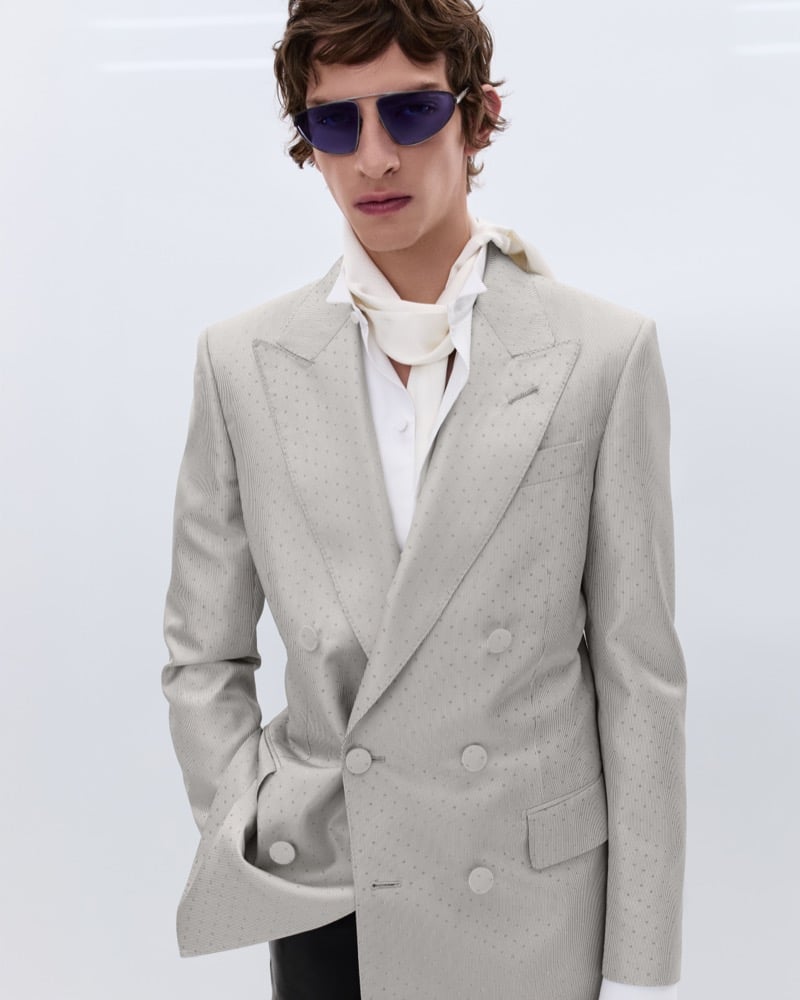 Elliot Belot wears blue-tinted aviator sunglasses with a cream textured double-breasted blazer over a white shirt and ivory silk scarf