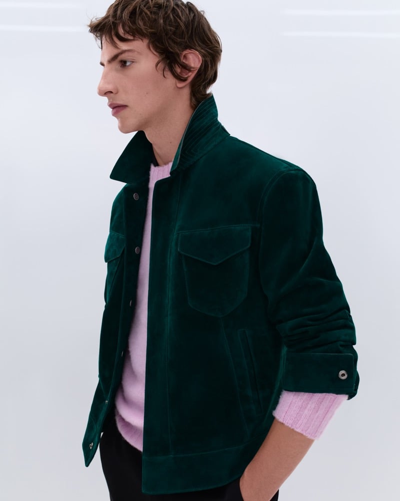 Elliot Belot wears a forest green suede shirt jacket over a pale pink ribbed wool crewneck sweater