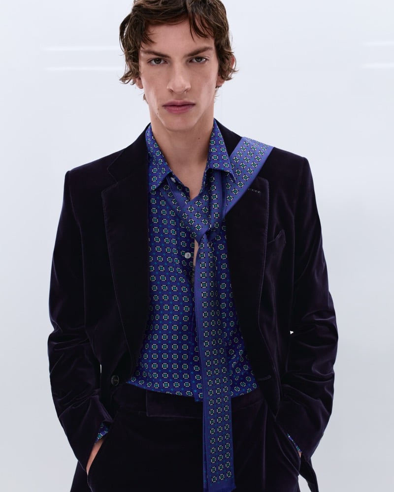 Elliot Belot wears a midnight blue velvet blazer over a blue medallion print silk shirt with a matching long silk scarf draped at the neck