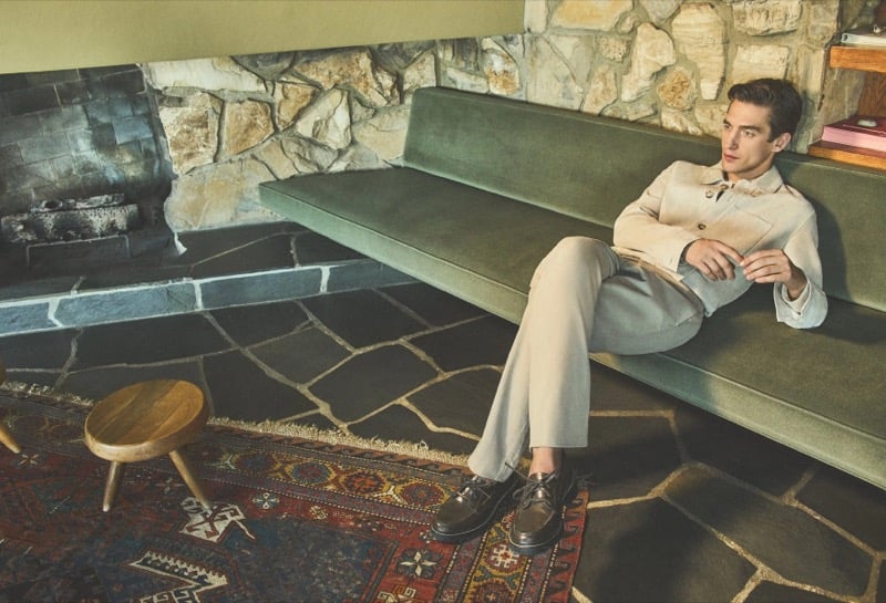 Anatol Modzelewski reclines on a sage green velvet sofa wearing a cream cotton overshirt jacket, stone tailored trousers, and brown leather derbies for Vince spring 2026