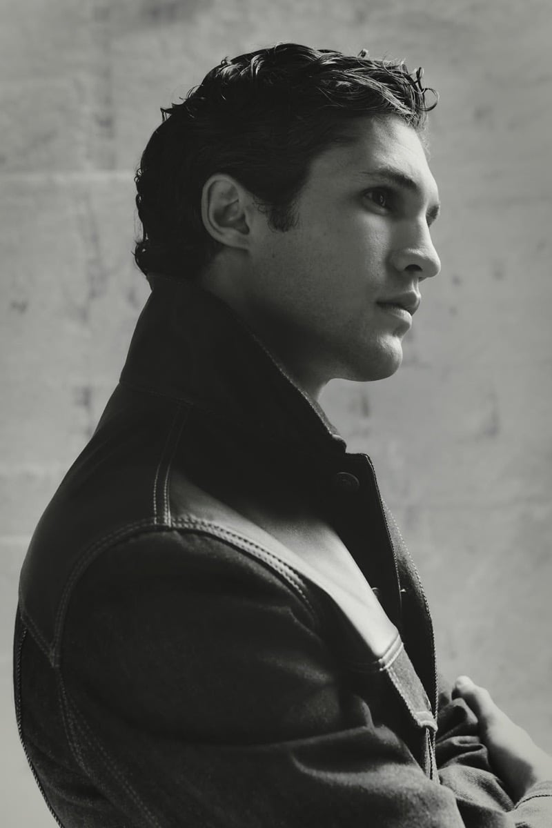 Black-and-white profile portrait of Francisco Henriques in a leather-yoke denim trucker jacket against a textured stone wall for Brunello Cucinelli's fall 2026 edit