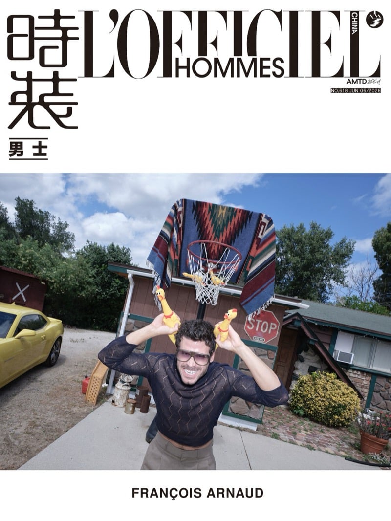 François Arnaud holds two rubber chickens overhead under a patterned rug caught in a basketball hoop