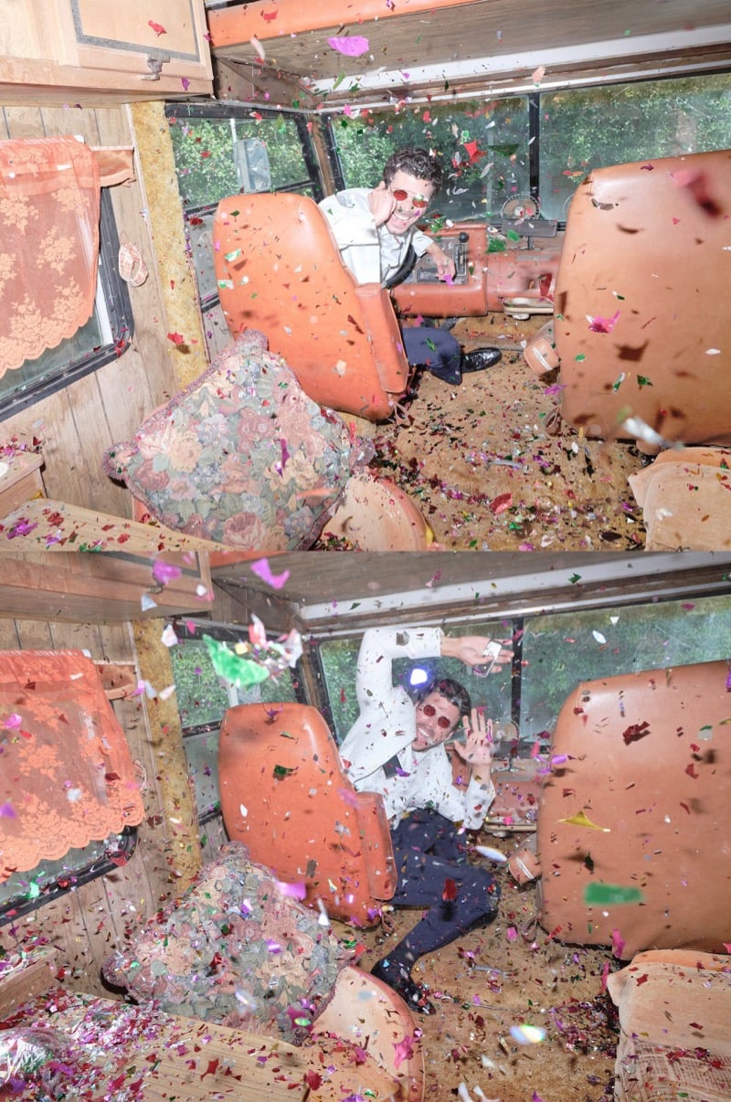 François Arnaud sits amid a confetti explosion inside a retro camper lined with orange furniture