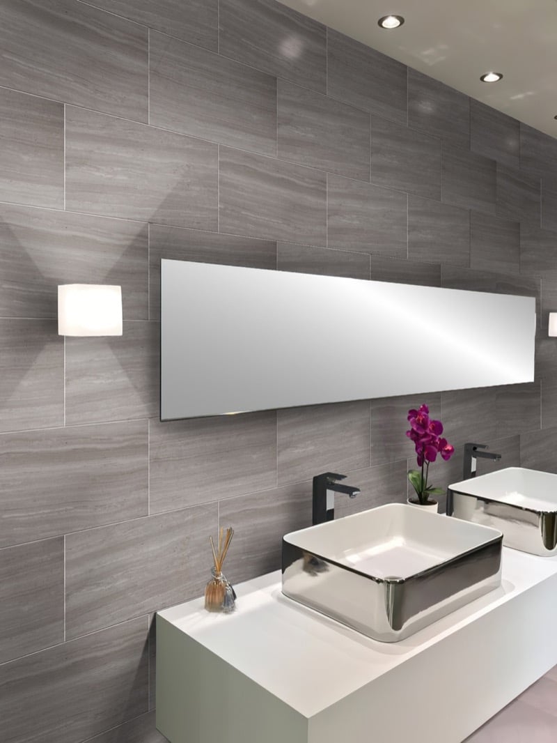 Wood-look gray tile wall behind a wall-mounted mirror and dual vessel sink vanity in a modern bathroom