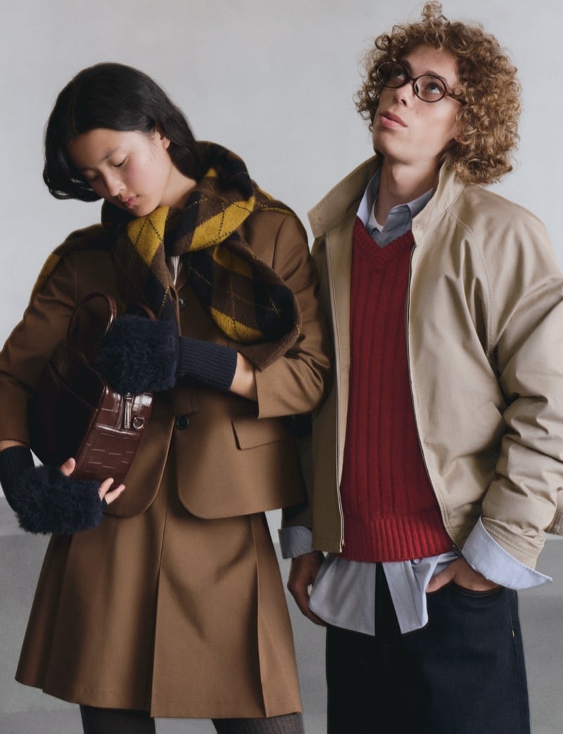 Two GU models, one in a camel skirt suit with an argyle scarf, the other in a tan jacket over a red sweater vest looking upward