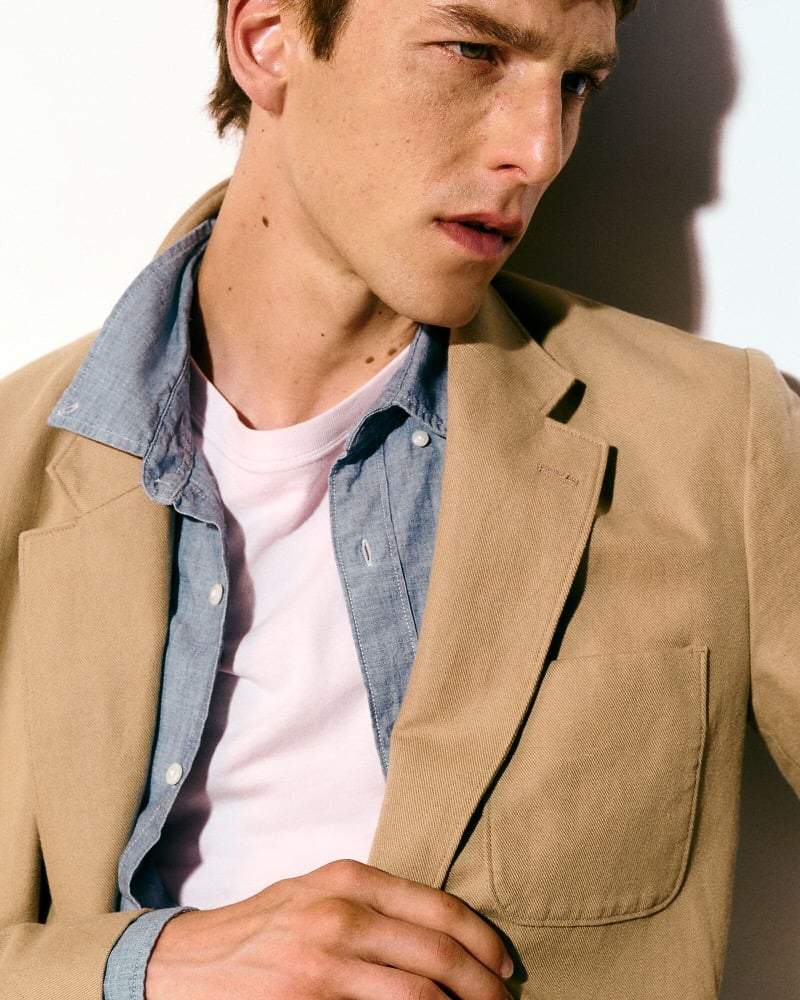Quentin Demeester in a tan cotton-linen suit jacket worn open over a chambray shirt