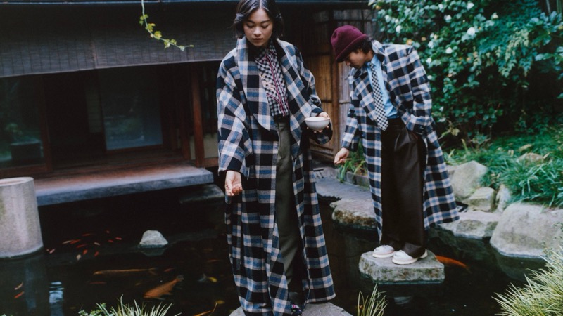 Lukita Maxwell and Nico Hiraga in matching checked Kenzo coats stand beside a koi pond in a Japanese garden