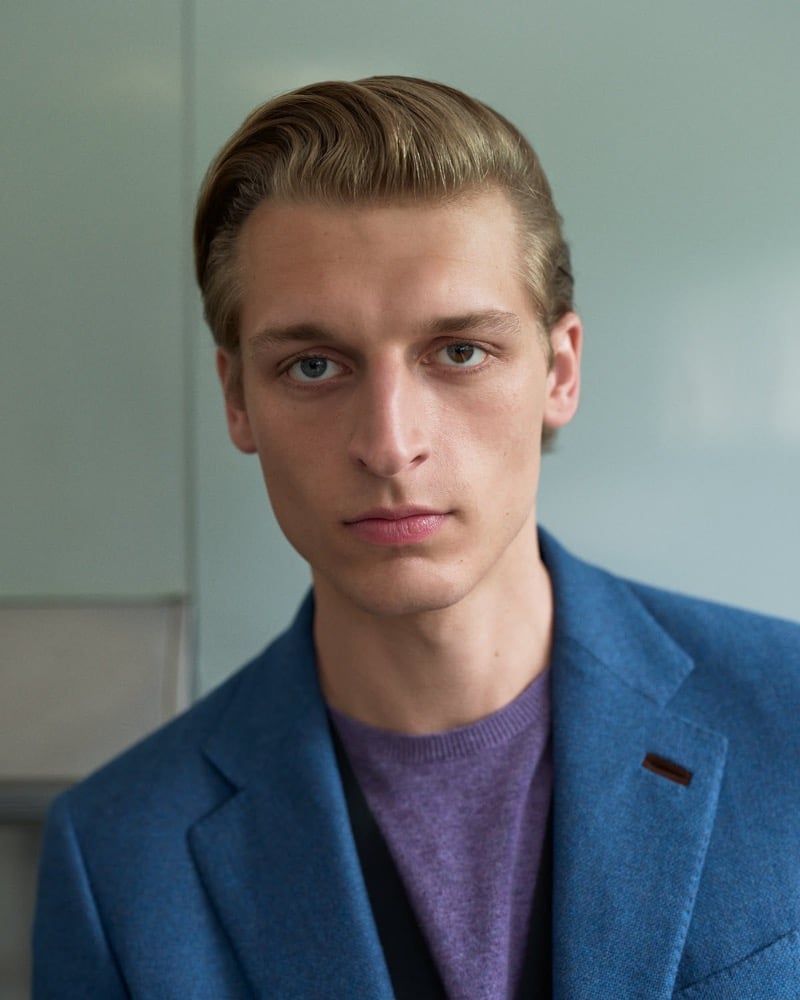 Close-up portrait of Colin Otto in a blue tweed blazer over a purple sweater against a soft green wall