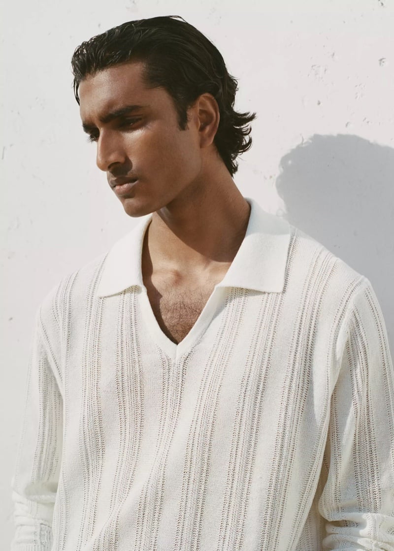 Close-up of Jeenu Mahadevan in a white ribbed knit polo shirt looking to the side