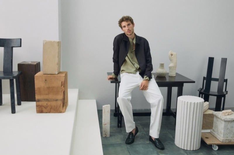 Aristide Deslandes takes a seat in a shirt jacket, linen shirt, and white trousers with leather loafers