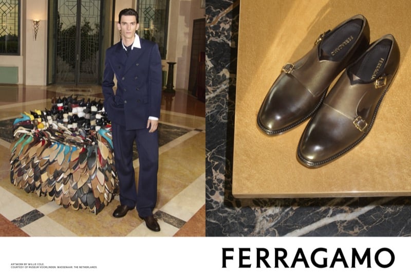 Thibaud Charon stands in a navy double-breasted suit beside Willie Cole's multicolored shoe sculpture, with a pair of Ferragamo monk strap shoes shown alongside