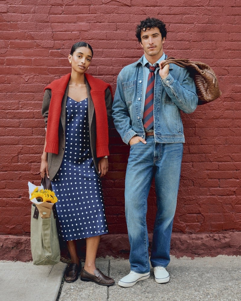 Raphael Diogo in a denim jacket and striped tie standing beside a female model in a polka dot dress holding sunflowers