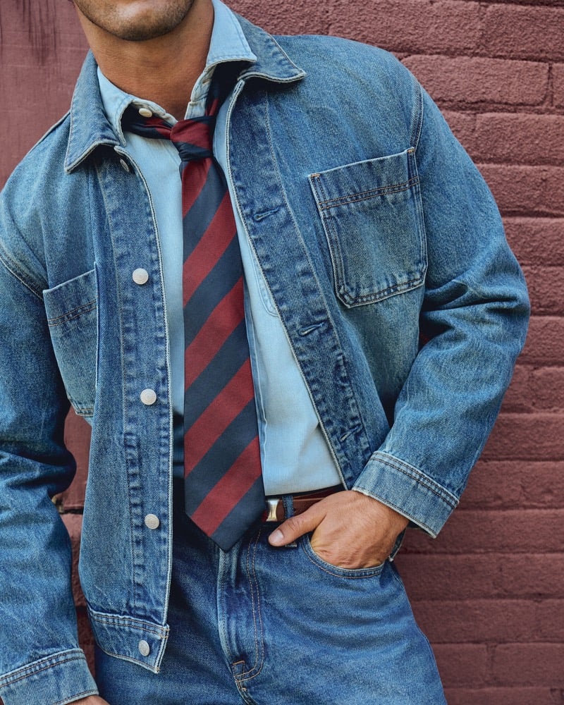 Close-up of Raphael Diogo in a denim jacket with a striped tie and leather belt