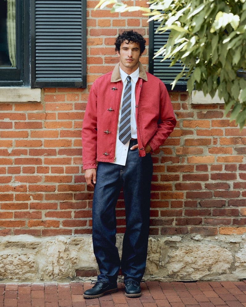 Raphael Diogo in a red canvas jacket with a corduroy collar over a striped tie and dark denim