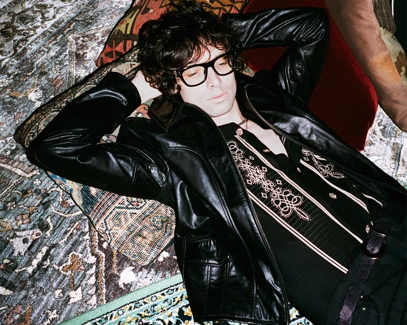 Chandler Lucy of The Hellp reclines on layered rugs in a leather jacket over an embroidered Western shirt for AMIRI's fall-winter 2026 campaign